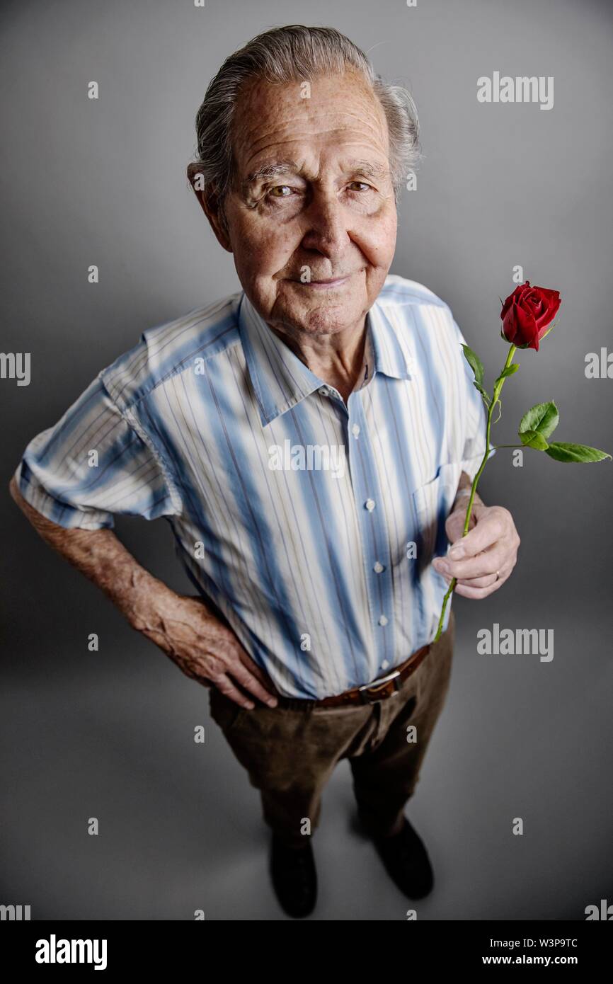 Senior detiene una rosa rossa in mano, simbolo foto amore, romanticismo, studio shot, Germania Foto Stock