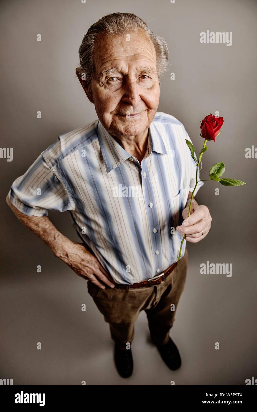 Senior detiene una rosa rossa in mano, simbolo foto amore, romanticismo, studio shot, Germania Foto Stock