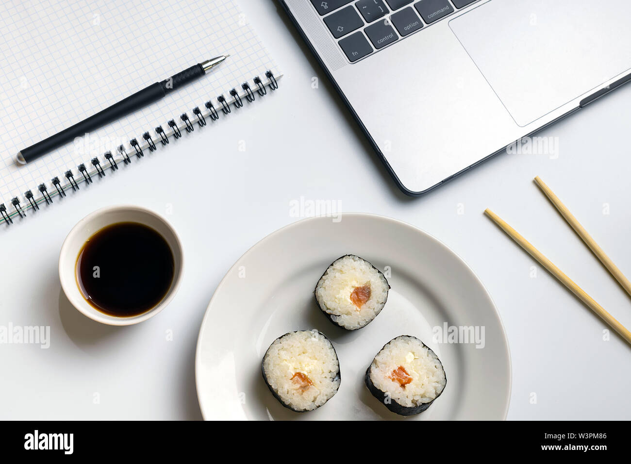 Tempo di interruzione per mangiare sushi. Rotoli di sushi snacking sul lavoro. Laptop e notebook su bianco organizzate escursioni. Foto Stock