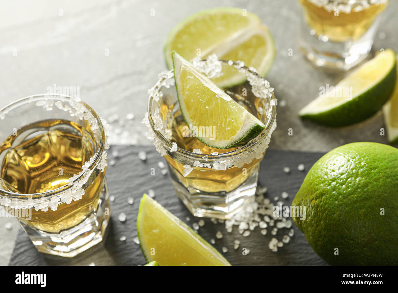 Scatti di Tequila con sale e fettine di lime su sfondo grigio Foto Stock