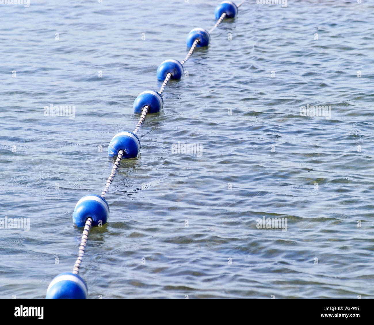 Stringa di blu e bianco boe sulle calme acque del lago. Utilizzate come marcatori di confine per limitare l'area nuoto Foto Stock
