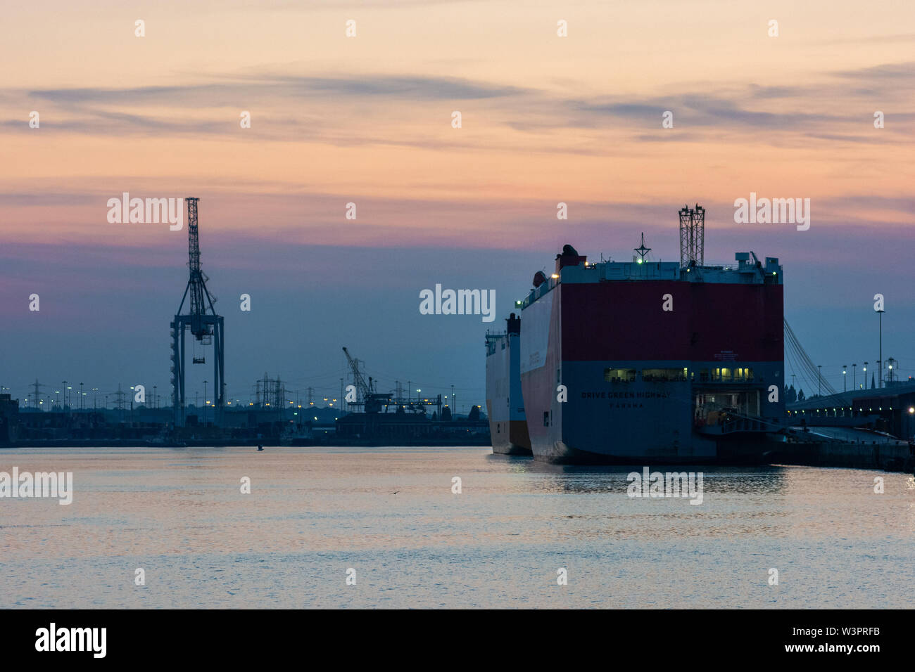Le navi da carico a Southampton docks al tramonto su una serata estiva, Hampshire, Regno Unito Foto Stock