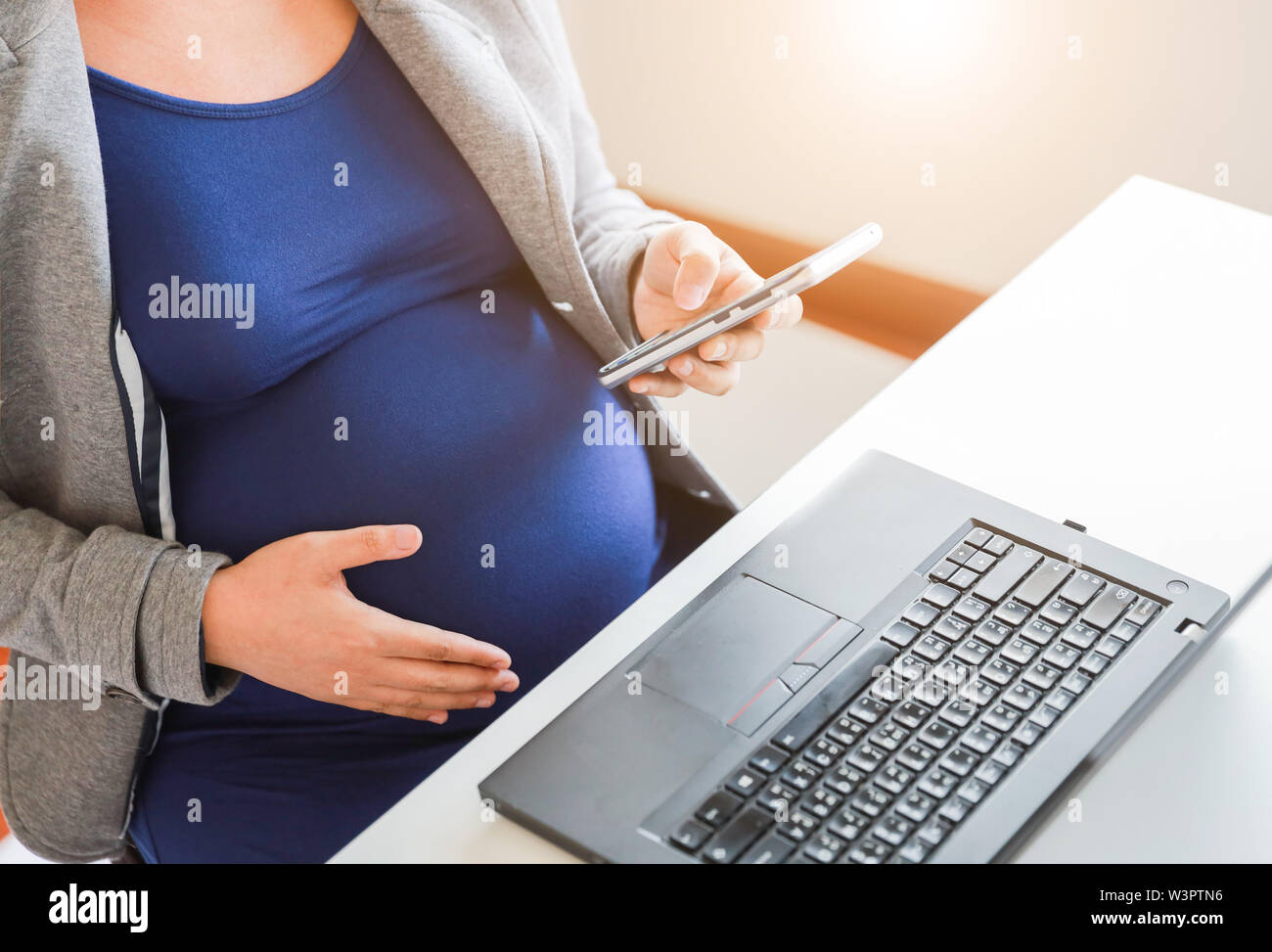 donna incinta sta lavorando su computer portatile e telefono cellulare, business Foto Stock