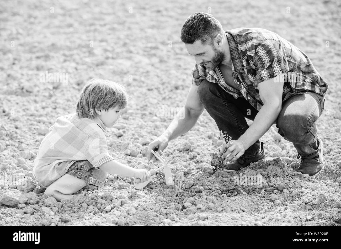 Piccolo bambino aiutare il padre in agricoltura. ricco terreno naturale. Eco farm. padre e figlio piantare fiori in massa. nuova vita. suoli fertilizzanti. felice giornata della terra. Albero di famiglia. La giornata della terra. Seduto sul terreno. Foto Stock