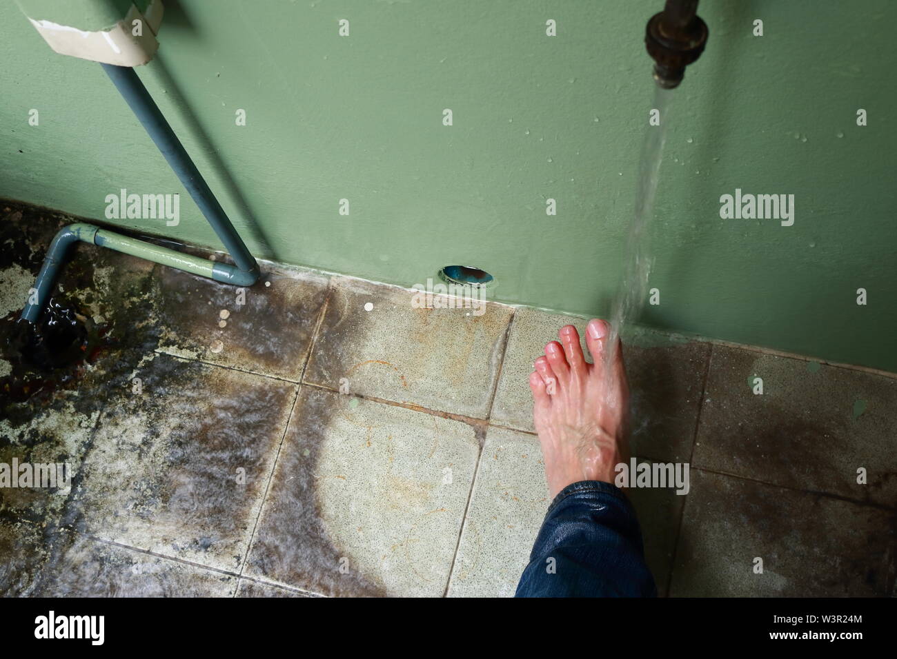 Movimento sfocate di acqua che scorre sul piede sinistro e le dita dei piedi di un uomo asiatico Foto Stock
