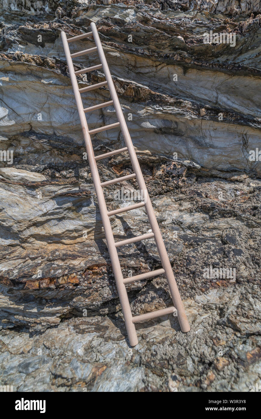 Piccolo giocattolo di legno scaletta sostennero contro la scogliera. Metafora la scalata di carriera, salire sull'alloggiamento scaletta, scala aziendale, arrampicata sociale. Foto Stock