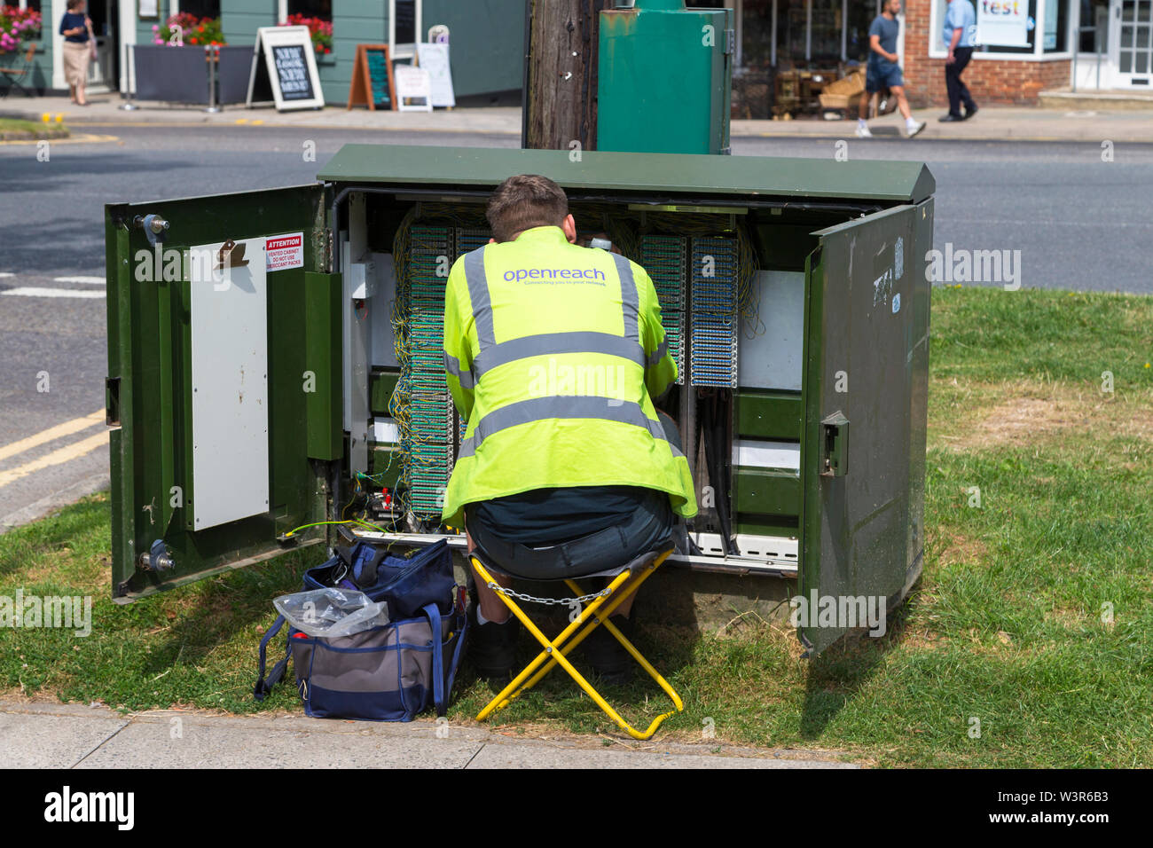 Ingegnere Openreach seduti ad un armadio elettrico, tenterden, high street, kent, Regno Unito Foto Stock
