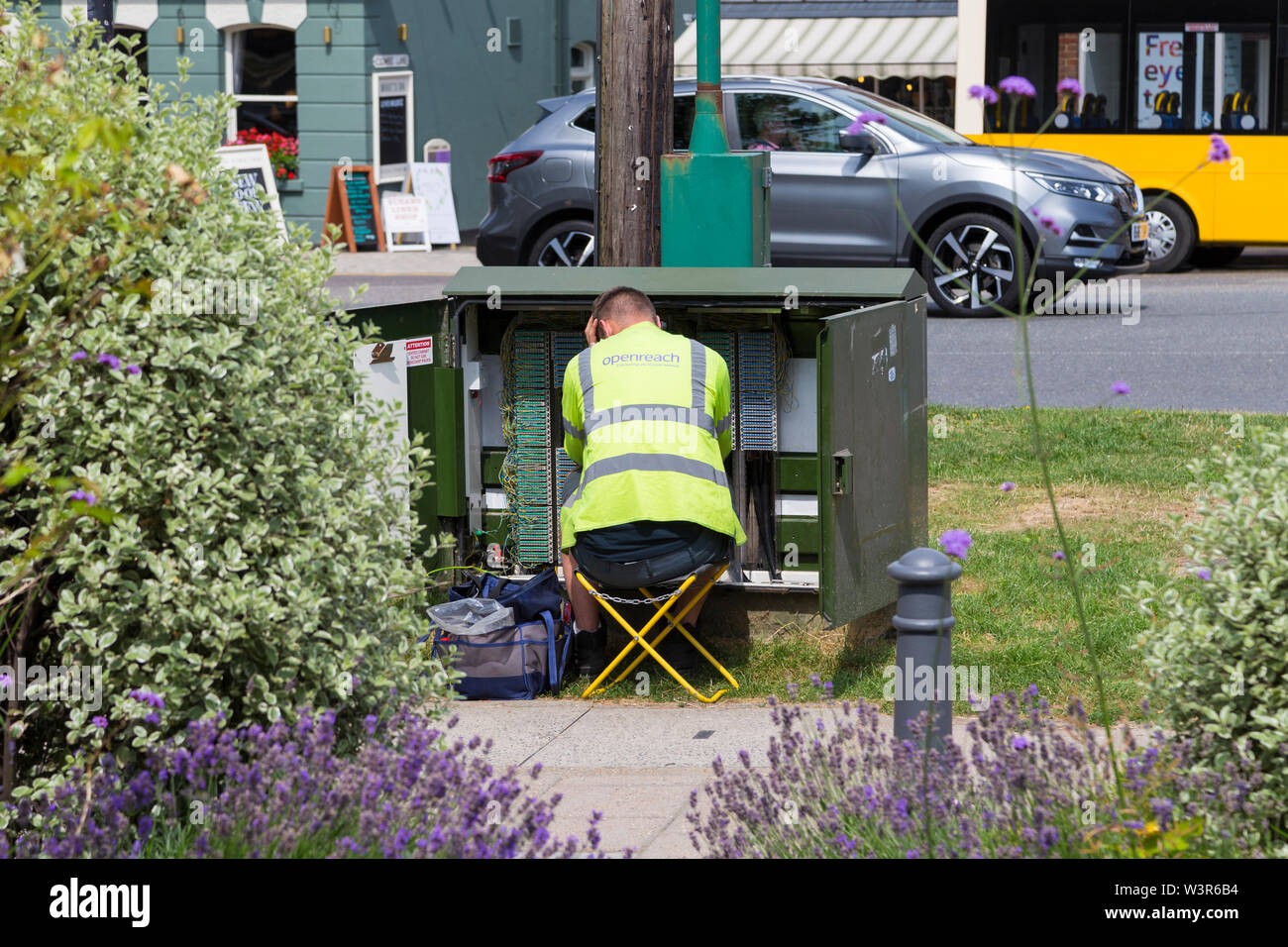 Ingegnere Openreach seduti ad un armadio elettrico, tenterden, high street, kent, Regno Unito Foto Stock