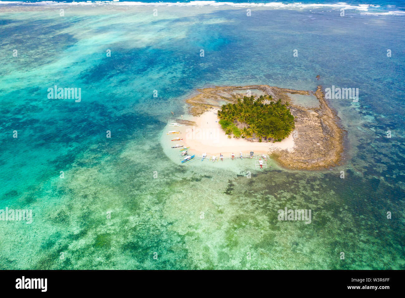 Piccola isola paradiso sulla barriera corallina, vista dall'alto. Guyam isola, Siargao, Filippine. Isola tropicale con palme e lagune. Barche e persone su una piccola isola. Foto Stock