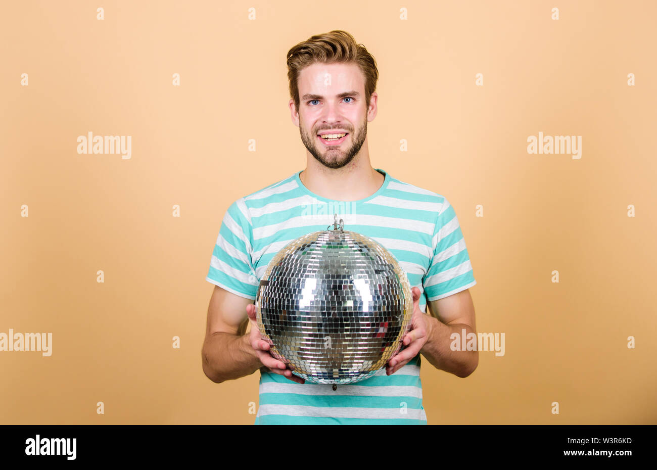 Ragazzo che vi invitano a parte. Migliaia di minuscoli specchi che riflettono la creazione delle luci di atmosfera da discoteca. Come circa la parte. Allegro dj uomo. Uomo bello tenere palla da discoteca. Danze da discoteca night club. Musica retrò. Foto Stock