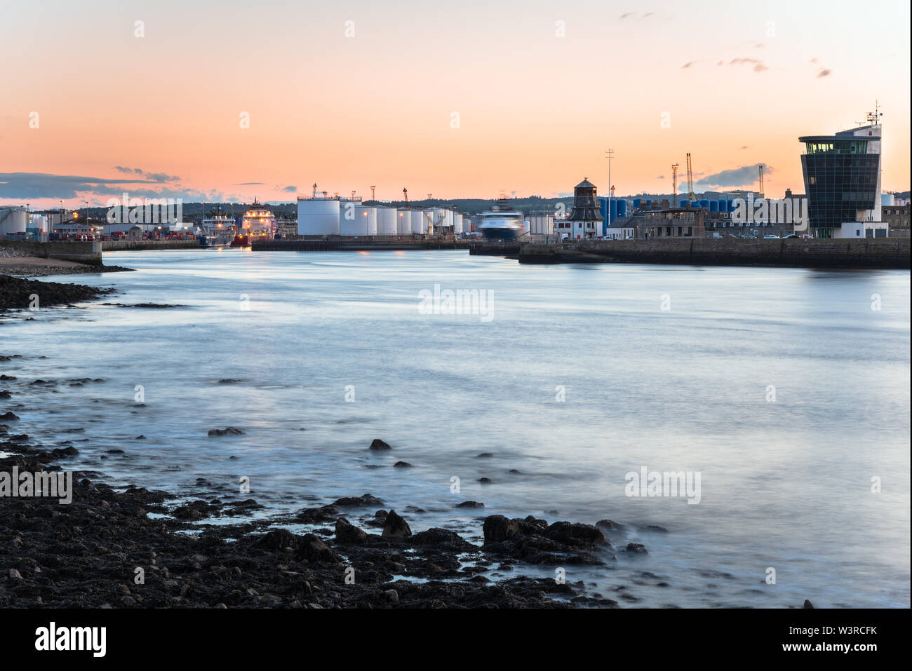 Vista di un porto industriale con i serbatoi del carburante e i depositi su piloni a crepuscolo Foto Stock