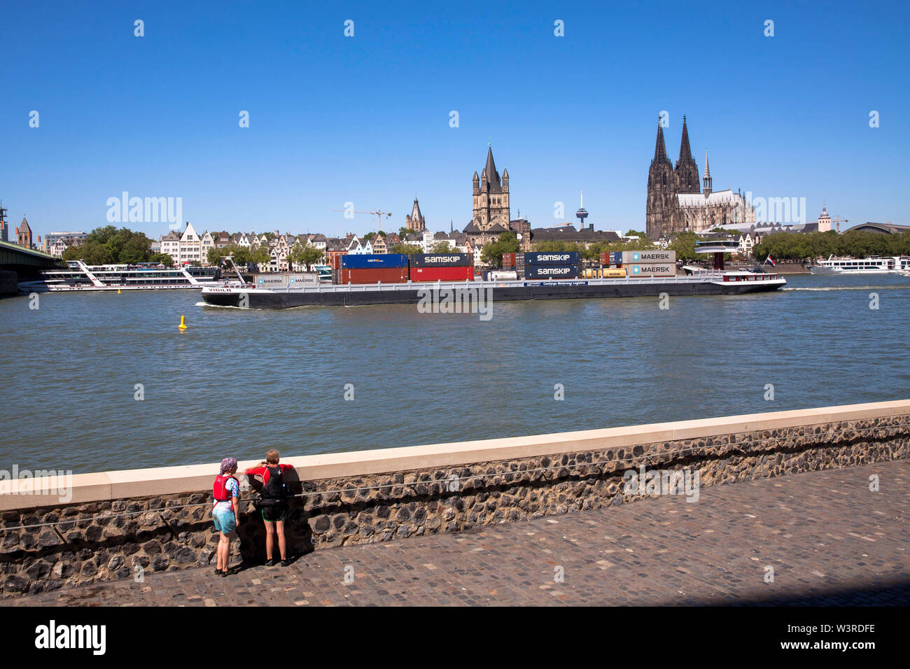 Contenitore nave sul fiume Reno presso la parte vecchia della città con la chiesa romanica lordi di San Martino e la cattedrale di Colonia, Germania. Conati Foto Stock