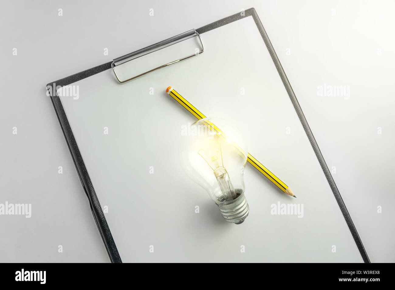 Carta bianca con un bulbo di luce e matita in attesa di idea concetto con luce Foto Stock