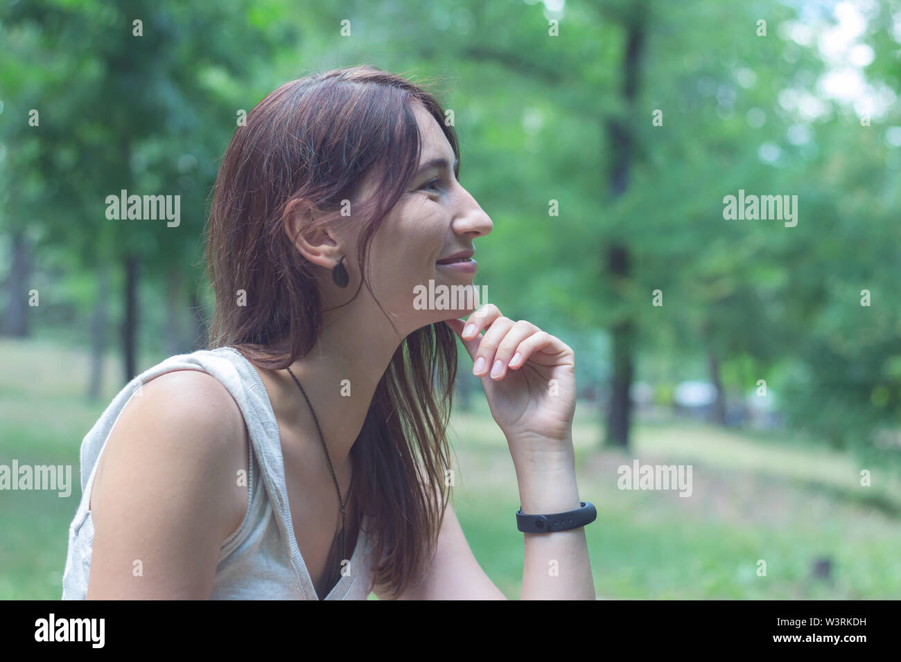 Una donna con una luce e un dolce sorriso guarda lontano. Foto Stock