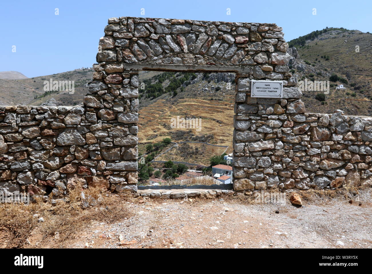 Muro di pietra e una vista attraverso un cancello abbandonati a Hydra Island, Grecia. Foto Stock