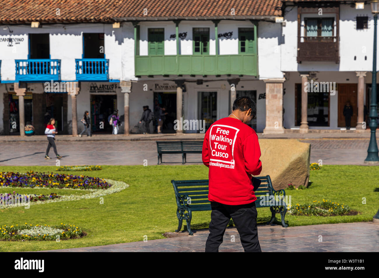 Gita a piedi in guida maglione rosso sul suo telefono cellulare in Plaza de Armas, Cusco, Perù, Sud America Foto Stock