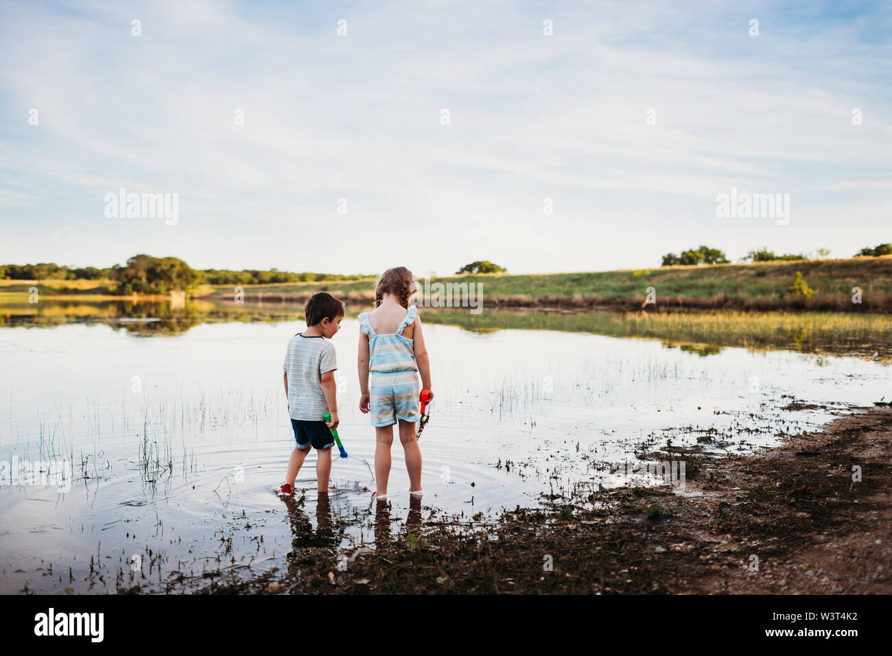 Ragazzo e ragazza cerca di pescare con reti a lago Foto Stock