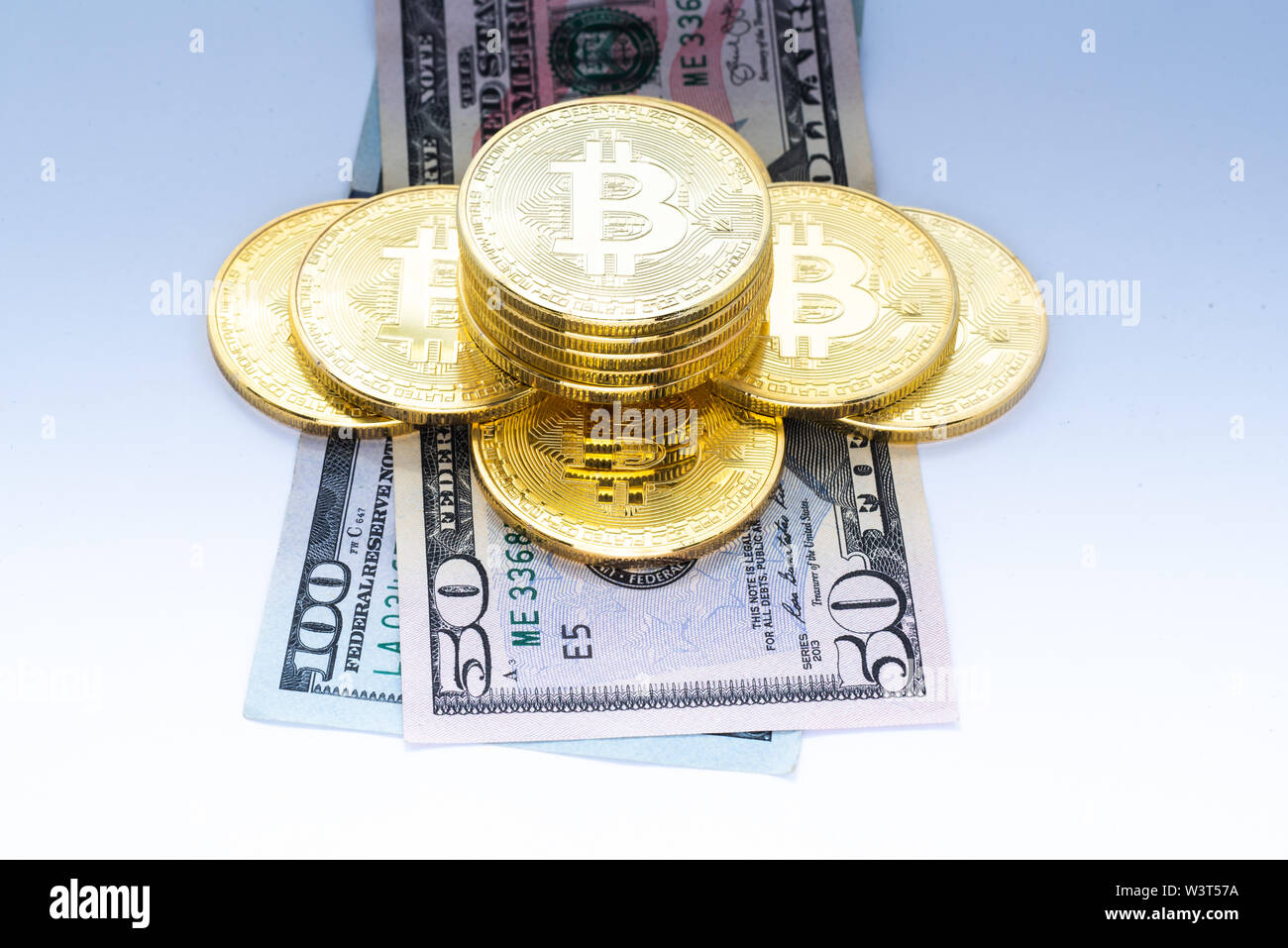 Un mucchio di colore oro bitcoins su $50 e $100 US valuta le fatture isolato. Foto Stock