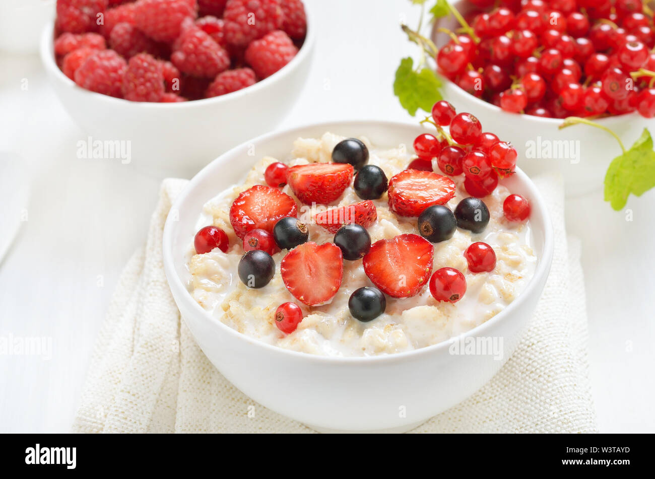 Una gustosa crema di farina e di latte con fette di fragola, nero e rosso di uve secche di Corinto nella ciotola, close up Foto Stock