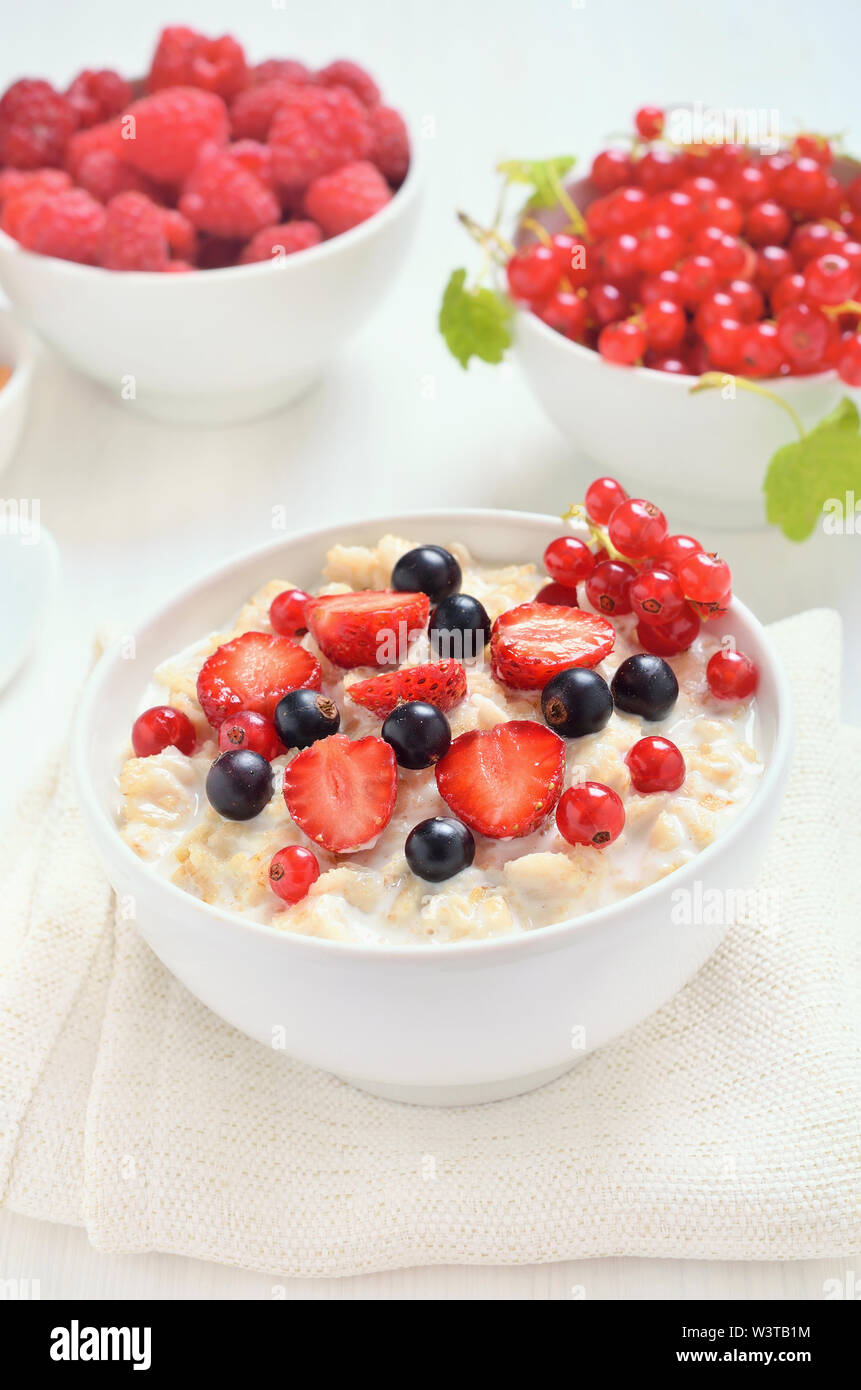 Una gustosa crema di farina e di latte con fette di fragola, nero e rosso di uve secche di Corinto nella ciotola, close up Foto Stock