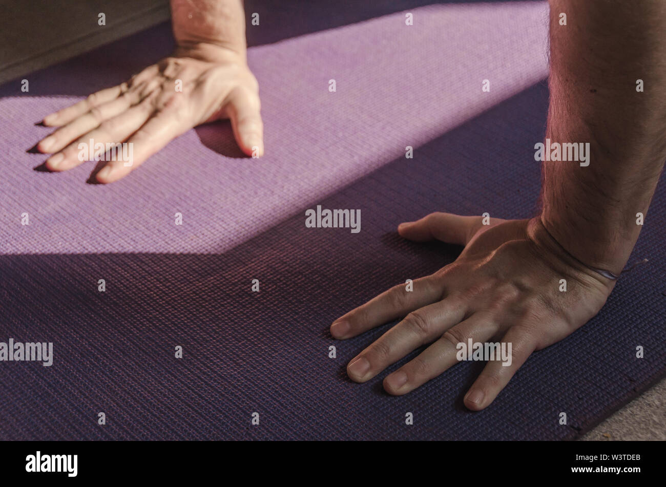 Close up man mano mentre facendo una postura yoga su un tappeto colorati. Lo Yoga, sano e il concetto di benessere Foto Stock