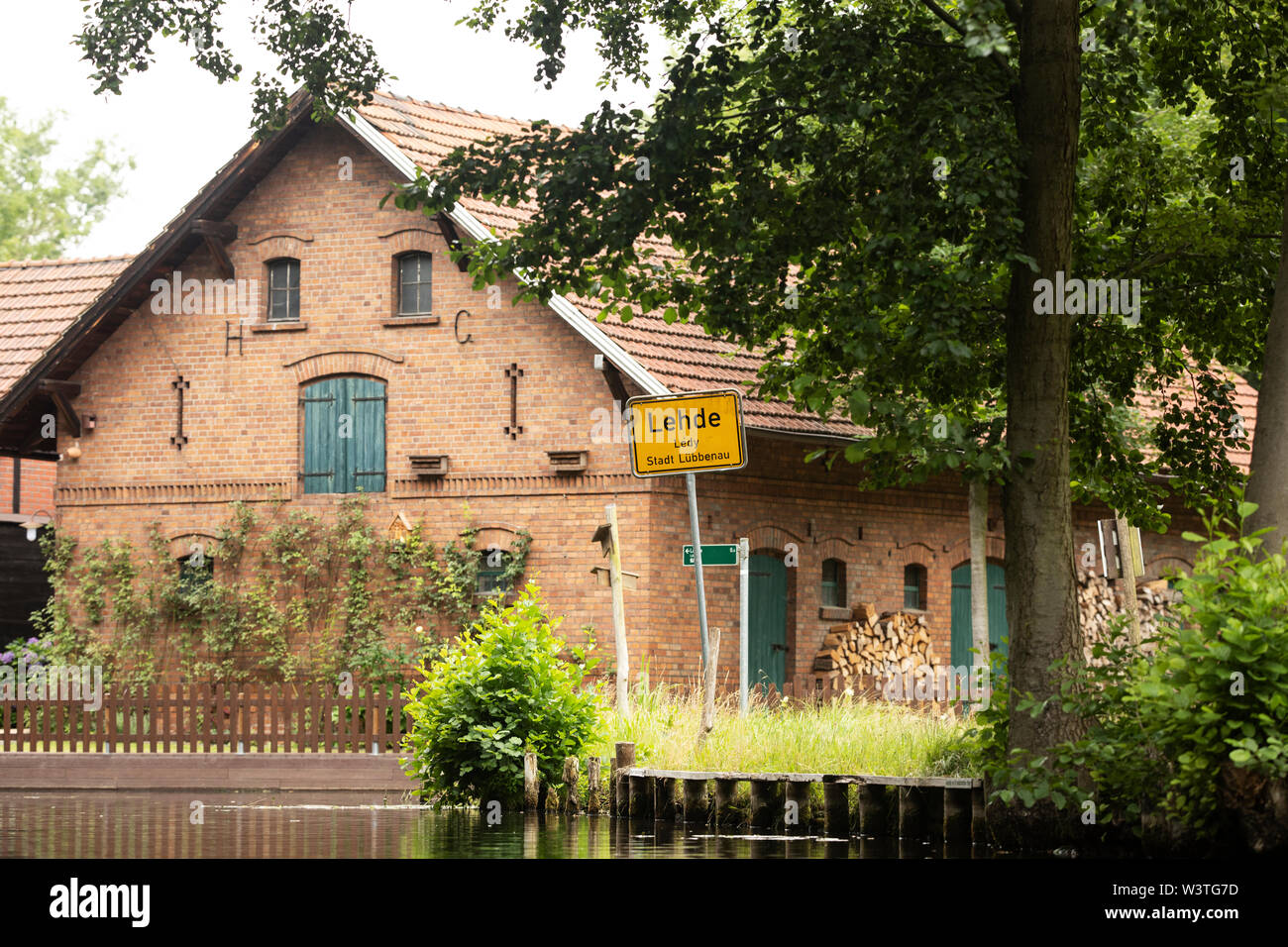 Un cartello che indica l'ingresso nel villaggio di Lehde sui canali della regione di Spreewald, Lübbenau, Germania, accanto a un'incantevole casa in mattoni. Foto Stock