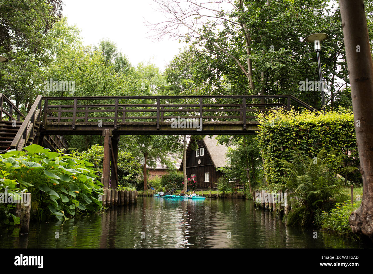 I kayak passano sotto un ponte pedonale a Lehde, un villaggio nello Spreewald a Lübbenau, in Germania. Foto Stock
