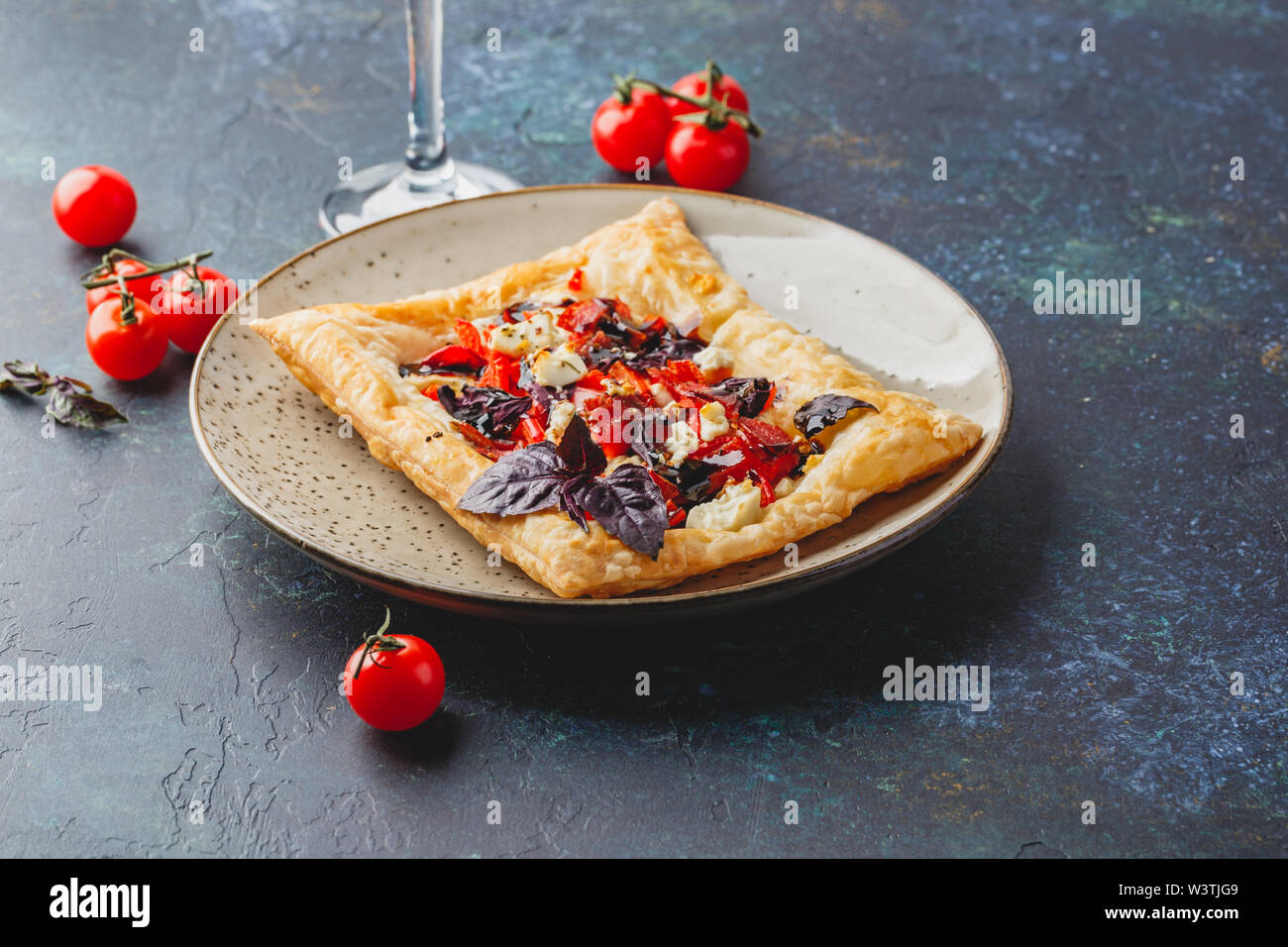 Pasta sfoglia canapes con pomodori, dolci peperoni, salame, formaggio feta e basilico viola. Foto Stock