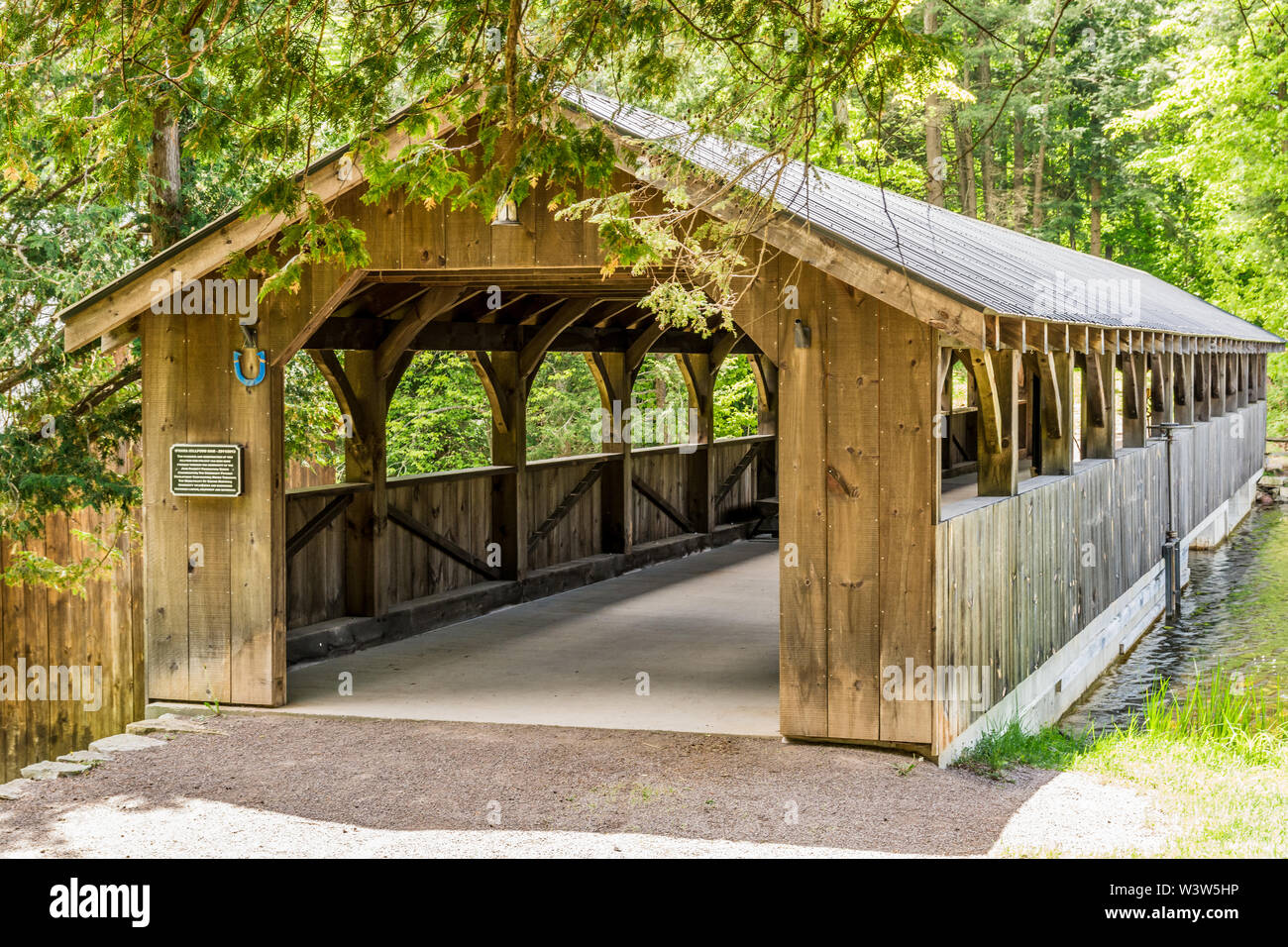 Storico ponte in legno d'epoca che riposa sotto l'ombra degli alberi Foto Stock