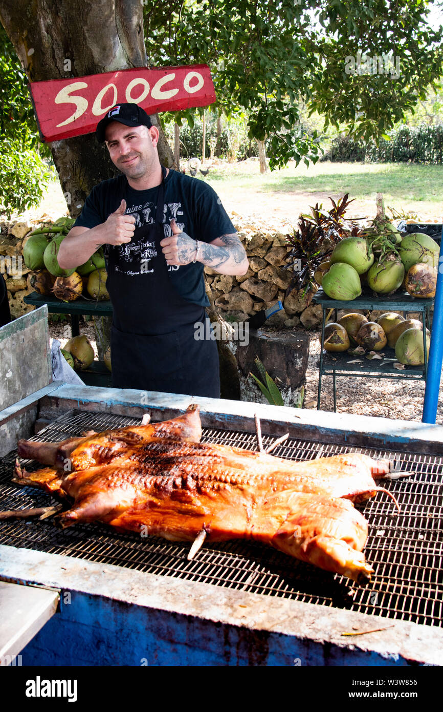Un uomo un arrosto di maiale su un fuoco aperto a l'Avana, Cuba Foto Stock