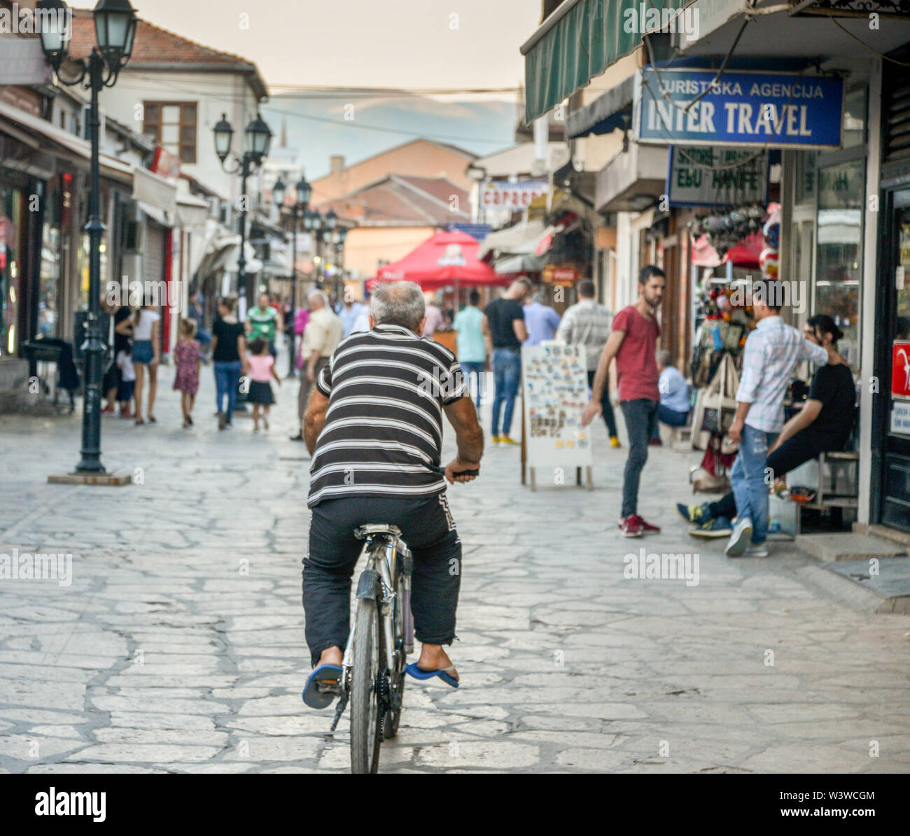 SKOPJE, Macedonia nord-Agosto 23 2019:uomo sulla bicicletta pedali lentamente lungo la strada principale di Vecchia Bazaar. Foto Stock