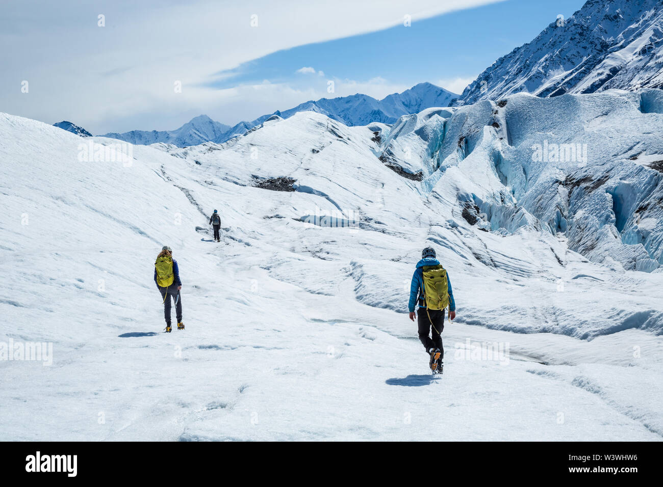 Tre di arrampicata e trekking guide escursionismo su ghiacciaio bianco ghiaccio. Essi camminano in ramponi fino il ghiacciaio Matanuska in remote Alaska. Foto Stock