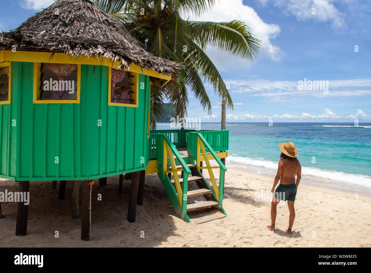 Shirtless uomo, sulla tenuta da bagno, accanto al green Beach Hut, Samoa Foto Stock
