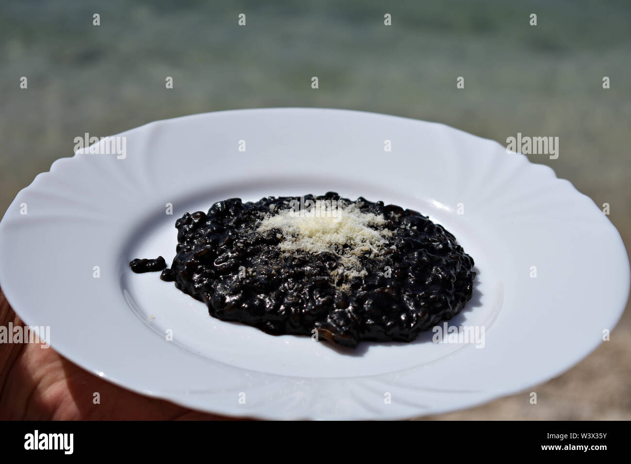 Nero deliziosi risotti serviti dal mare/ cameriere tenendo la piastra del risotto nero / cucina mediterranea - Immagine Foto Stock