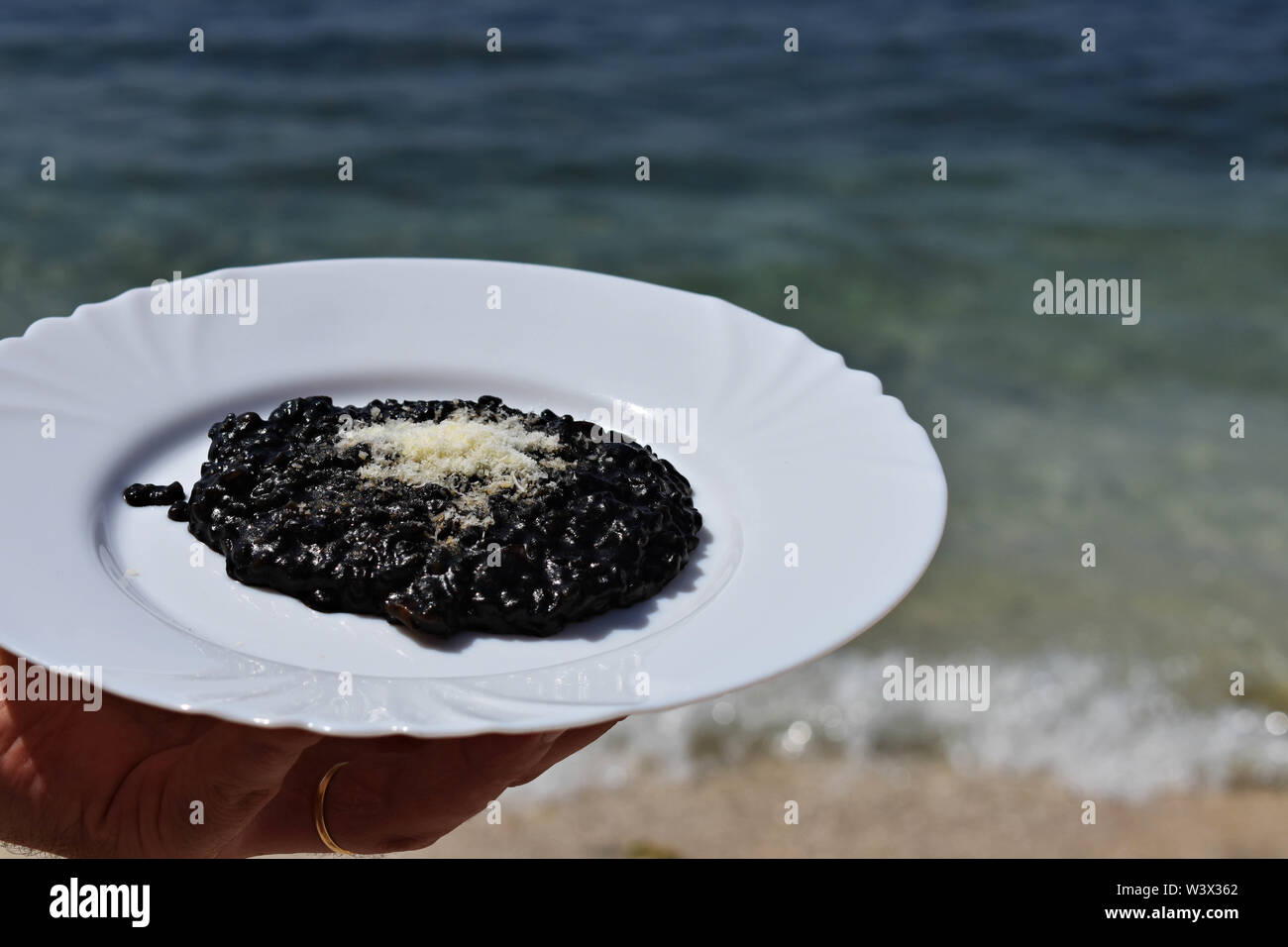 Nero deliziosi risotti serviti dal mare/ cameriere tenendo la piastra del risotto nero / cucina mediterranea - Immagine Foto Stock