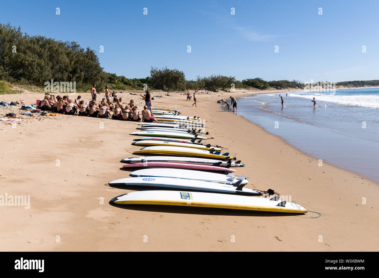 Un gruppo di giovani backpackers la loro prima lezione di surf con un istruttore presso Agnes Water Beach caravan e campeggio nel Queensland, in Australia. Foto Stock