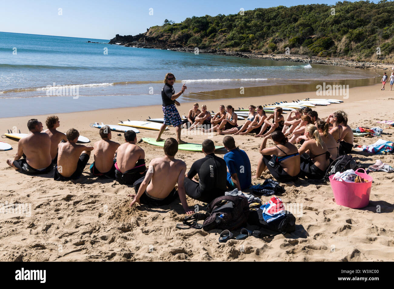 Un gruppo di giovani backpackers la loro prima lezione di surf con un istruttore presso Agnes Water Beach caravan e campeggio nel Queensland, in Australia. Foto Stock