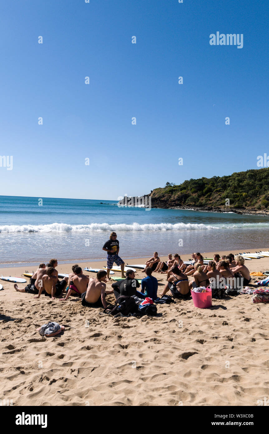 Un gruppo di giovani backpackers la loro prima lezione di surf con un istruttore presso Agnes Water Beach caravan e campeggio nel Queensland, in Australia. Foto Stock