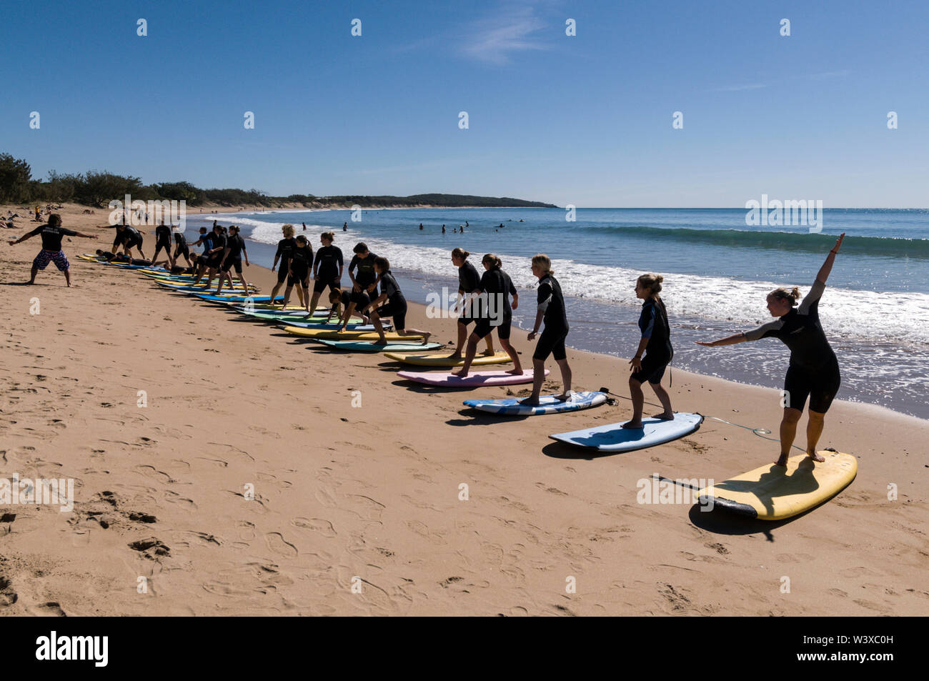 Un gruppo di giovani backpackers la loro prima lezione di surf con un istruttore presso Agnes Water Beach caravan e campeggio nel Queensland, in Australia. Foto Stock