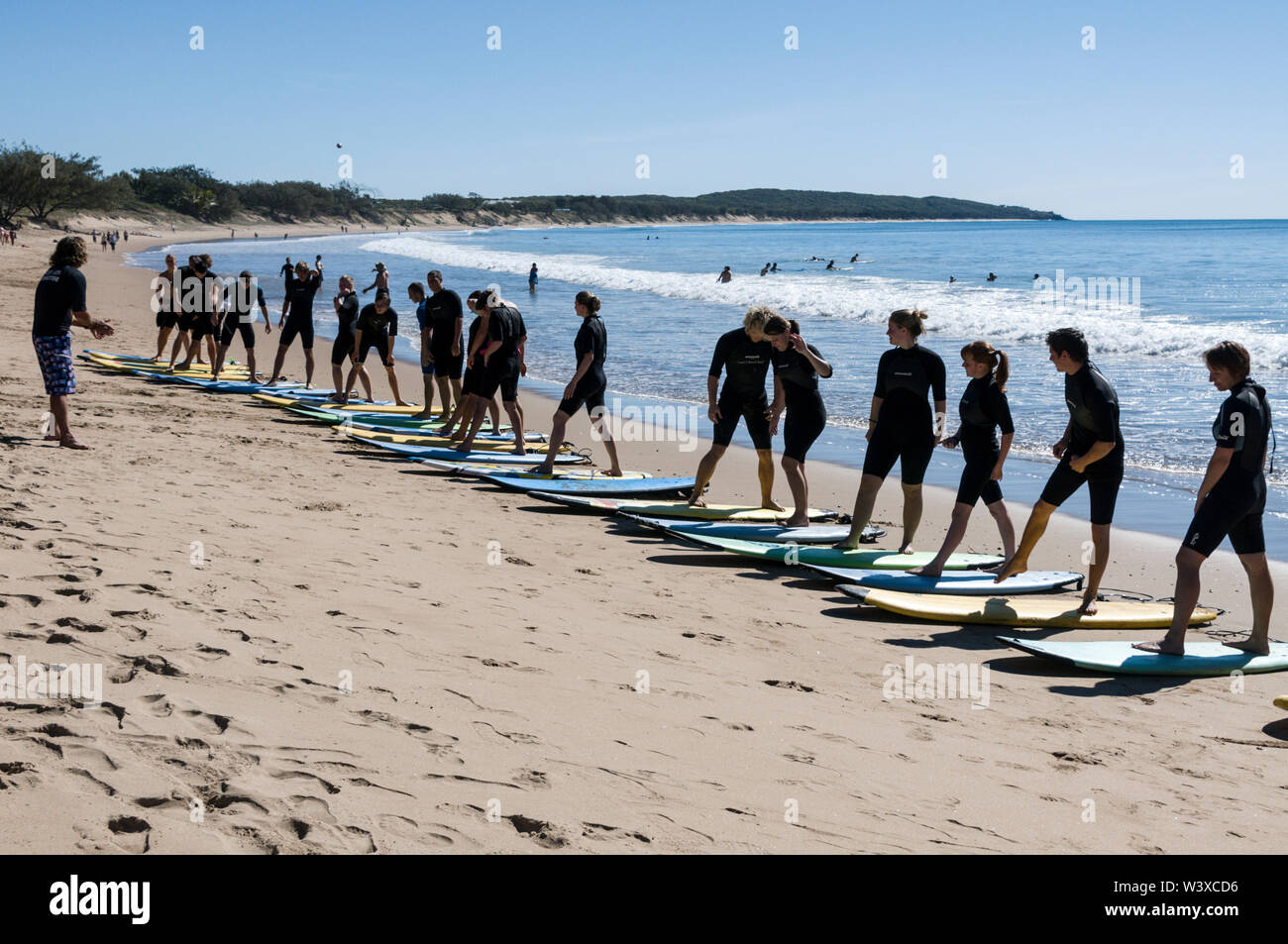 Un gruppo di giovani backpackers che hanno la loro prima lezione di surf con un istruttore a Agnes Water Beach Caravan e campeggio a Queensland, Australia. Foto Stock