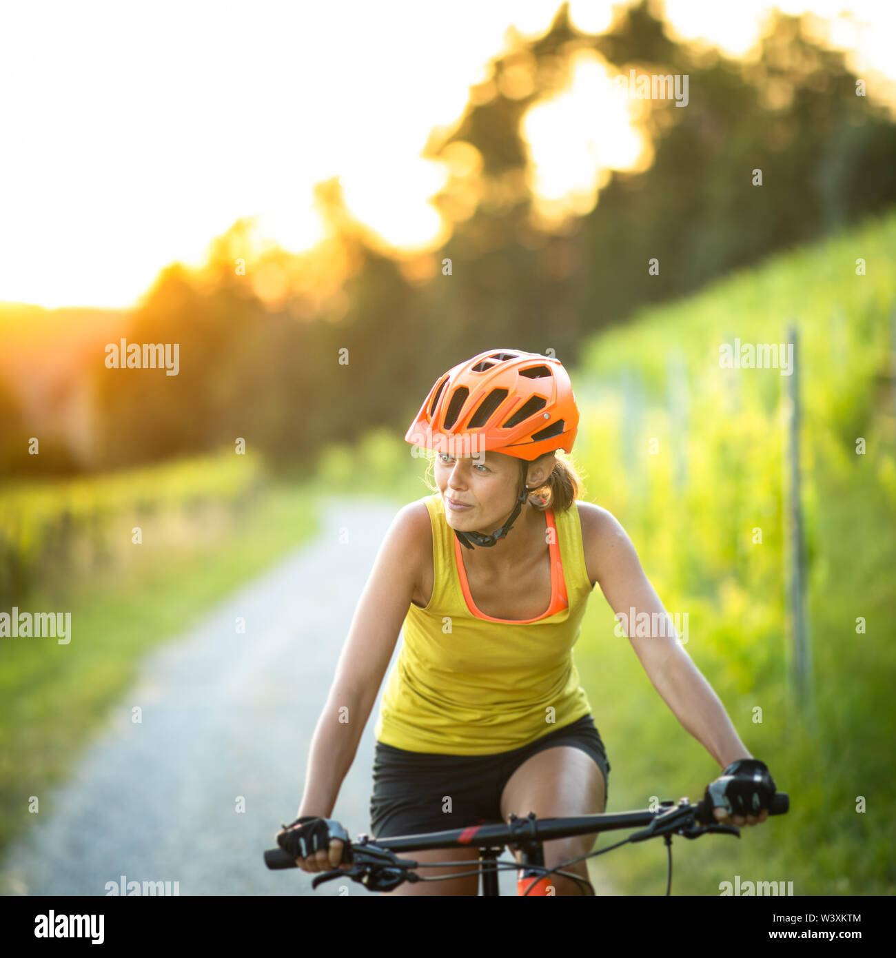 Piuttosto, giovane donna mountain bike su una mountain bike godendo di un sano stile di vita attivo all'aperto in estate (SHALLOW DOF) Foto Stock