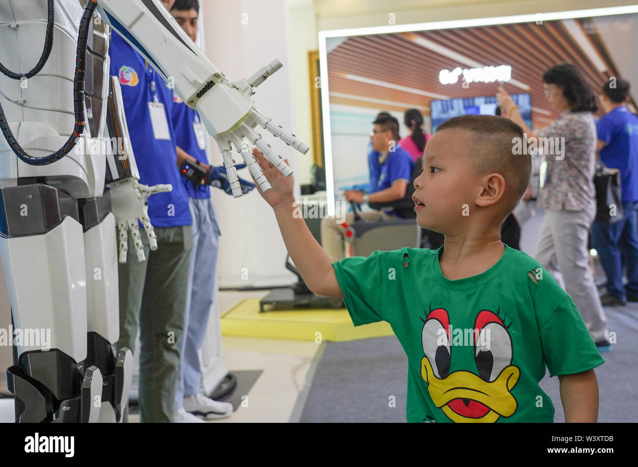 Pechino, Cina della provincia di Jiangxi. 18 Luglio, 2019. Un bambino stringe la mano con un robot durante una international mobile Internet delle cose (IOT) expo in Yingtan, Cina orientale della provincia di Jiangxi, luglio 18, 2019. Credito: Zhou Mi/Xinhua/Alamy Live News Foto Stock