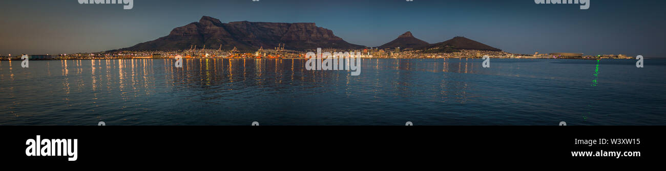 Le luci della città di Cape Town riflettono nelle acque della baia della tavola in una panoramica di una foto scattata da una nave nell'Oceano Atlantico. Foto Stock