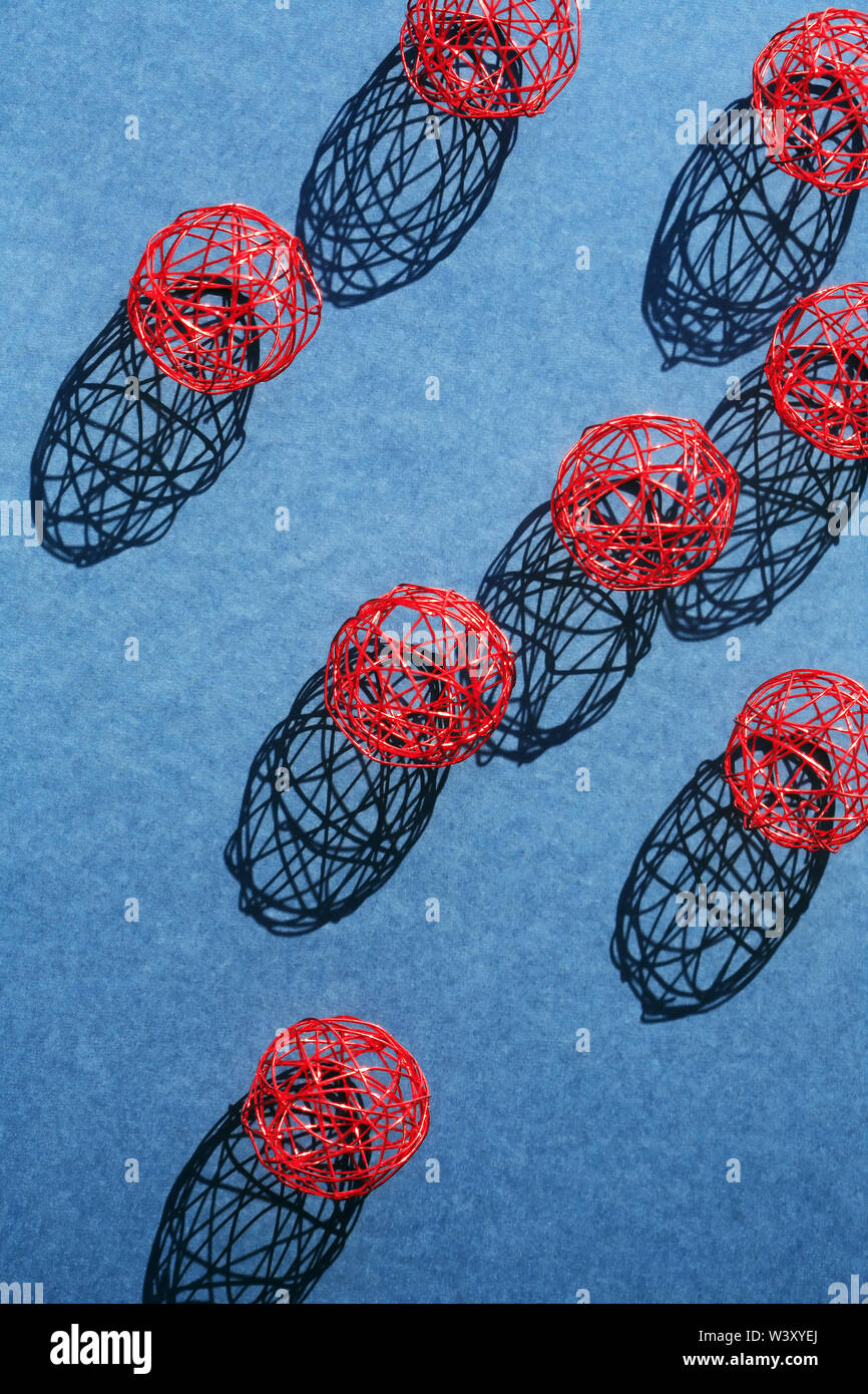 Set di palline rosse realizzate in filo metallico in una fila contro la luce solare Foto Stock