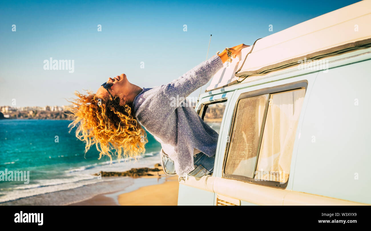 Viaggi e la felicità di stile - persone e vacanze estive con van - curly bionda bella donna piena di gioia al di fuori della finestra di un vecchio camper - Foto Stock