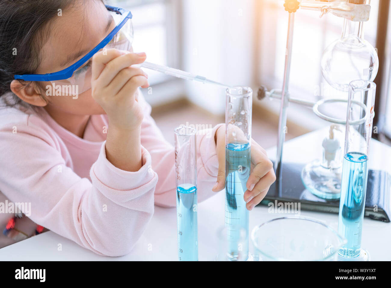 Bambino asiatico farmacia azienda pallone e tubo di prova nelle mani nel laboratorio di chimica di apprendimento esperimento. Scienziato la chimica e la scienza il concetto di istruzione. Bambini Foto Stock