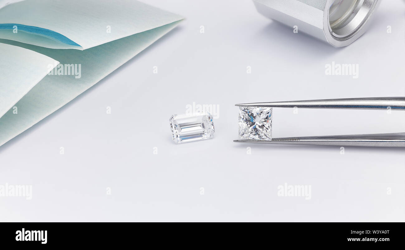 Grandi diamanti taglio Princess e taglio smeraldo diamante con la particella di diamante e Diamante pinzette con lente di ingrandimento su sfondo bianco Foto Stock