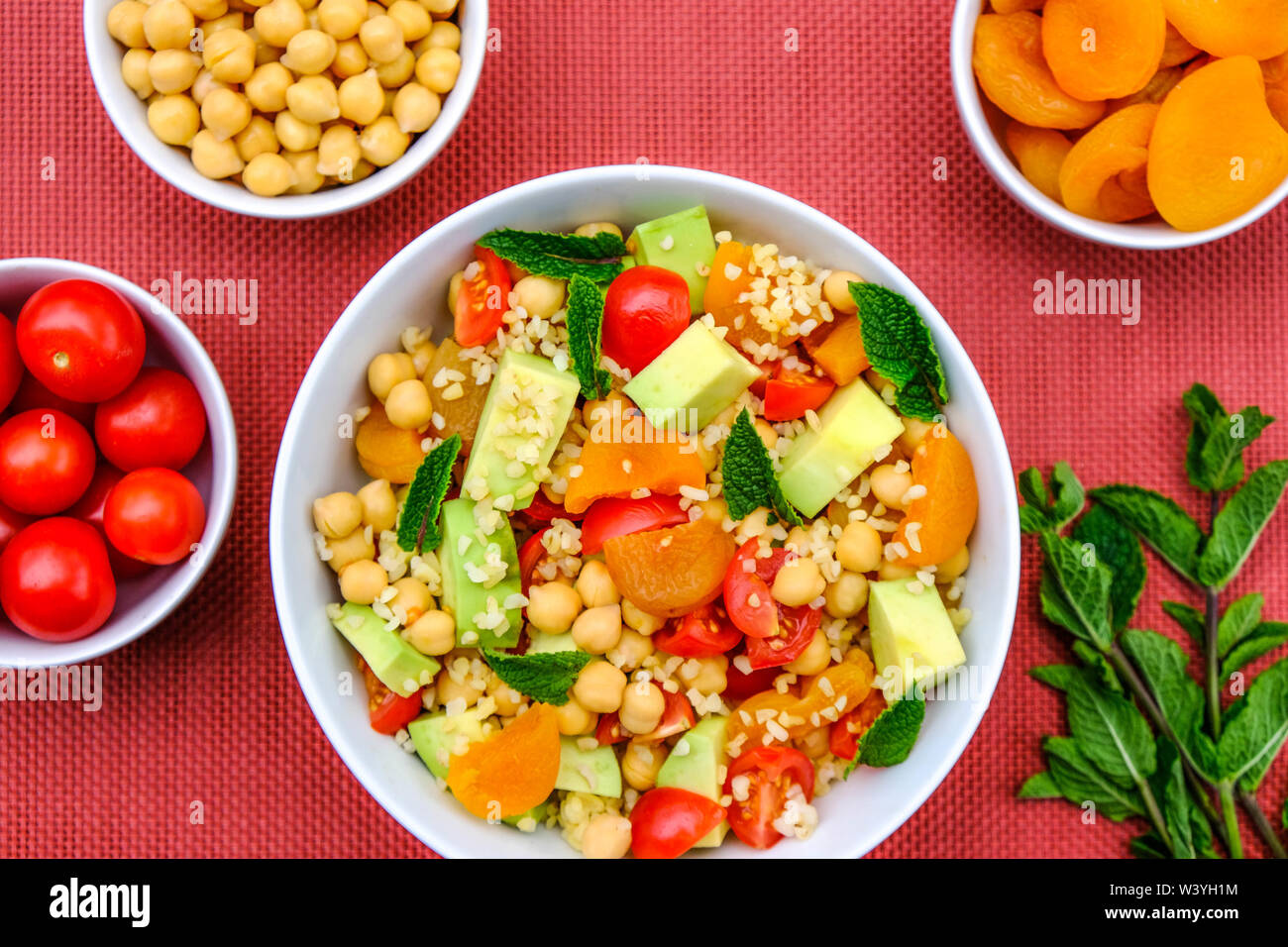 Una sana estate pranzo vegetariano ciotola con Avocado, pomodori ciliegini, ceci, couscous e albicocca secca Foto Stock