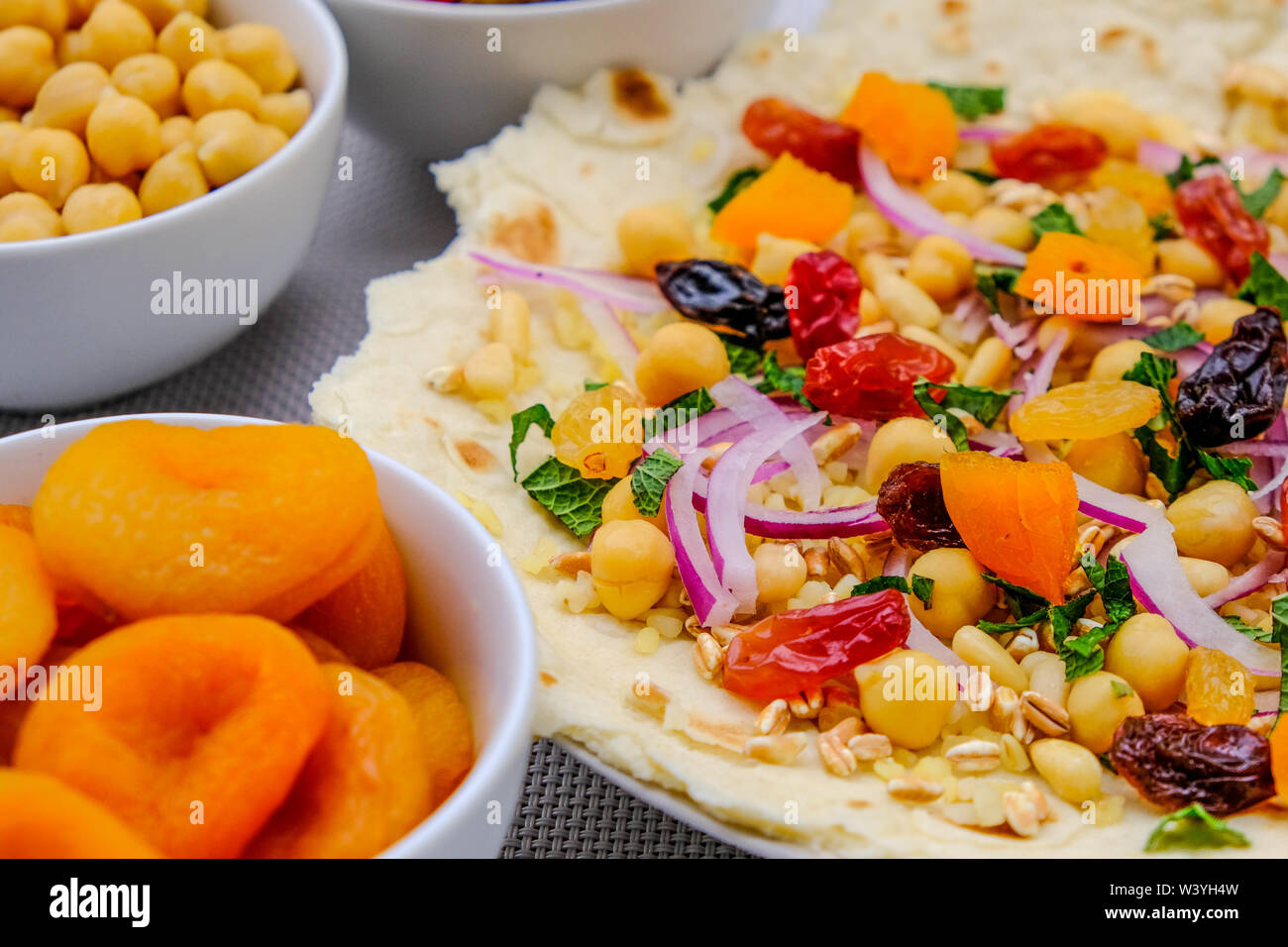 Una sana base di pizza con frutta e noci, albicocche, uva sultanina, uva passa, pinoli, cipolla rossa e ceci Foto Stock