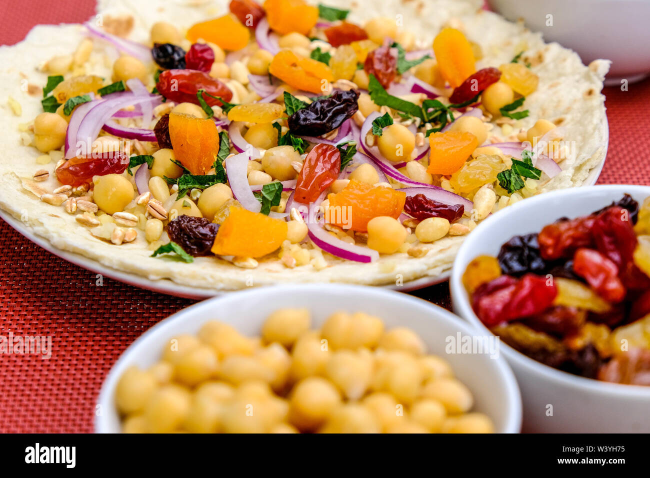 Una sana base di pizza con frutta e noci, albicocche, uva sultanina, uva passa, pinoli, cipolla rossa e ceci Foto Stock